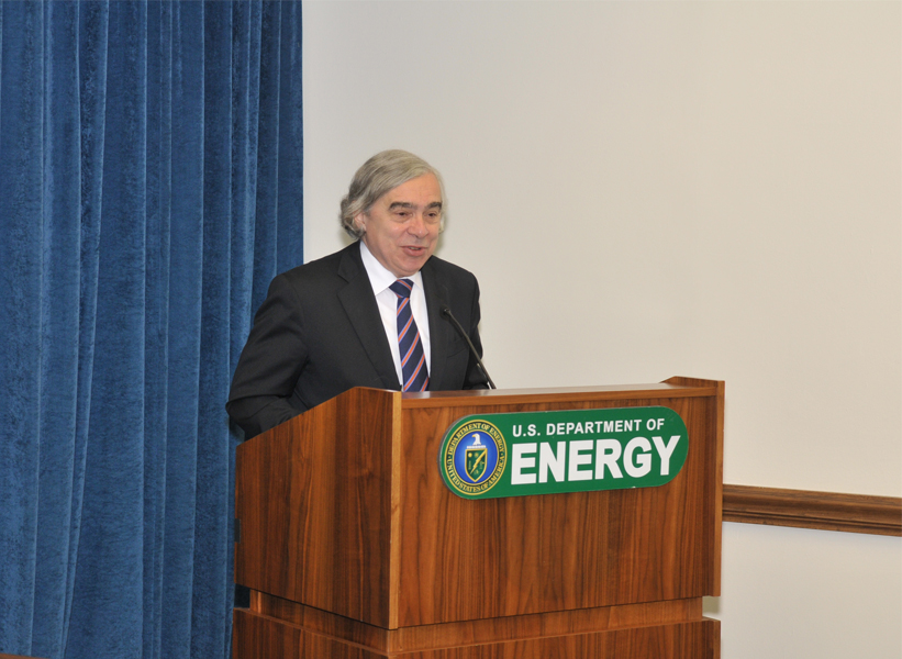 A man in a suit, standing behind a podium.