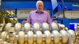 Andrew Hutton, associate director of Jefferson Lab’s Accelerator Division, looks over prototype particle accelerating devices – called cavities – in the lab’s Superconducting Radiofrequency Institute.