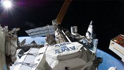 The AMS is visible on the ISS just after being installed, with a US Space Shuttle docked on the far right, a Russian Soyuz capsule docked on the far left.